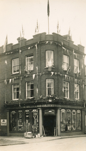 Black and white photo of the shop front decorated with flags